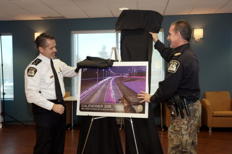 Le chef du Service de police de Laval, Pierre Brochet, et le maître-chien responsable du projet, Benoît Martel, dévoilent le calendrier. (Photo TC Media - Mario Beauregard) 