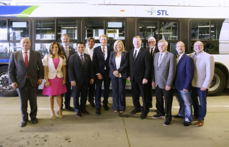 Marc Miller, secrétaire parlementaire du ministre de l'Infrastructure et des Collectivités, Francine Charbonneau, ministre responsable de la région de Laval et Marc Demers, maire, posent en compagnie de représentants des classes politiques municipale, provinciale et fédérale.