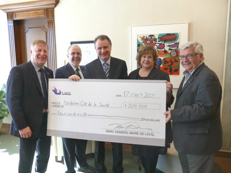 Marc Demers, maire; Alain Demers, directeur général de la Fondation de la Cité de la Santé; Louis Gaudreau, président du CA de la Fondation de la Cité de la Santé; Caroline Barbir, présidente-directrice générale, Centre intégré de santé et de services sociaux de Laval (CISSS); ainsi que Raynald Adams, membre du comité exécutif et conseiller de Renaud, posent avec le chèque de 200 000 $.