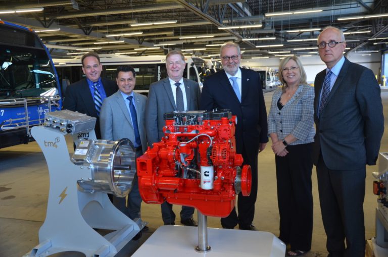 4,25 M$ pour des autobus électriques avec prolongateur d’autonomie Johnny Mulfati, directeur marché autobus – Cummins, David De Cotis, président du c.a. STL, Marc Demers, maire, Pierre Arcand, ministre de l’Énergie et des Ressources naturelles, Francine Charbonneau, ministre de la région, et Robert Baril, directeur général TM4 posent devant cette nouvelle technologie qui permettra de réduire les gaz à effet de serre (GES).