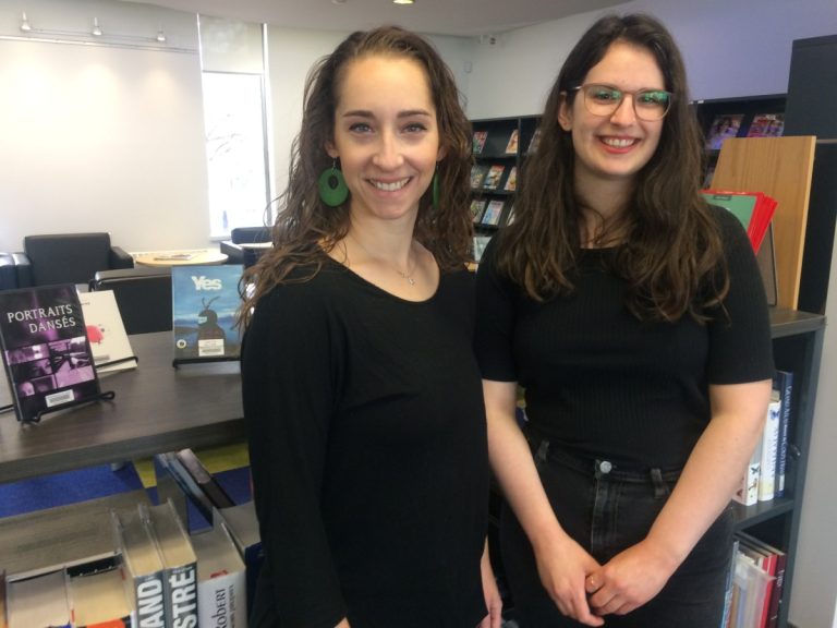 La chorégraphe Audrey Gaussiran et la bédéiste Myriam Bourgeois devant des œuvres de l'événement Fabriqué à/Made in Lavalp> à la bibliothèque Émile-Nelligan, dans Laval-des-Rapides.